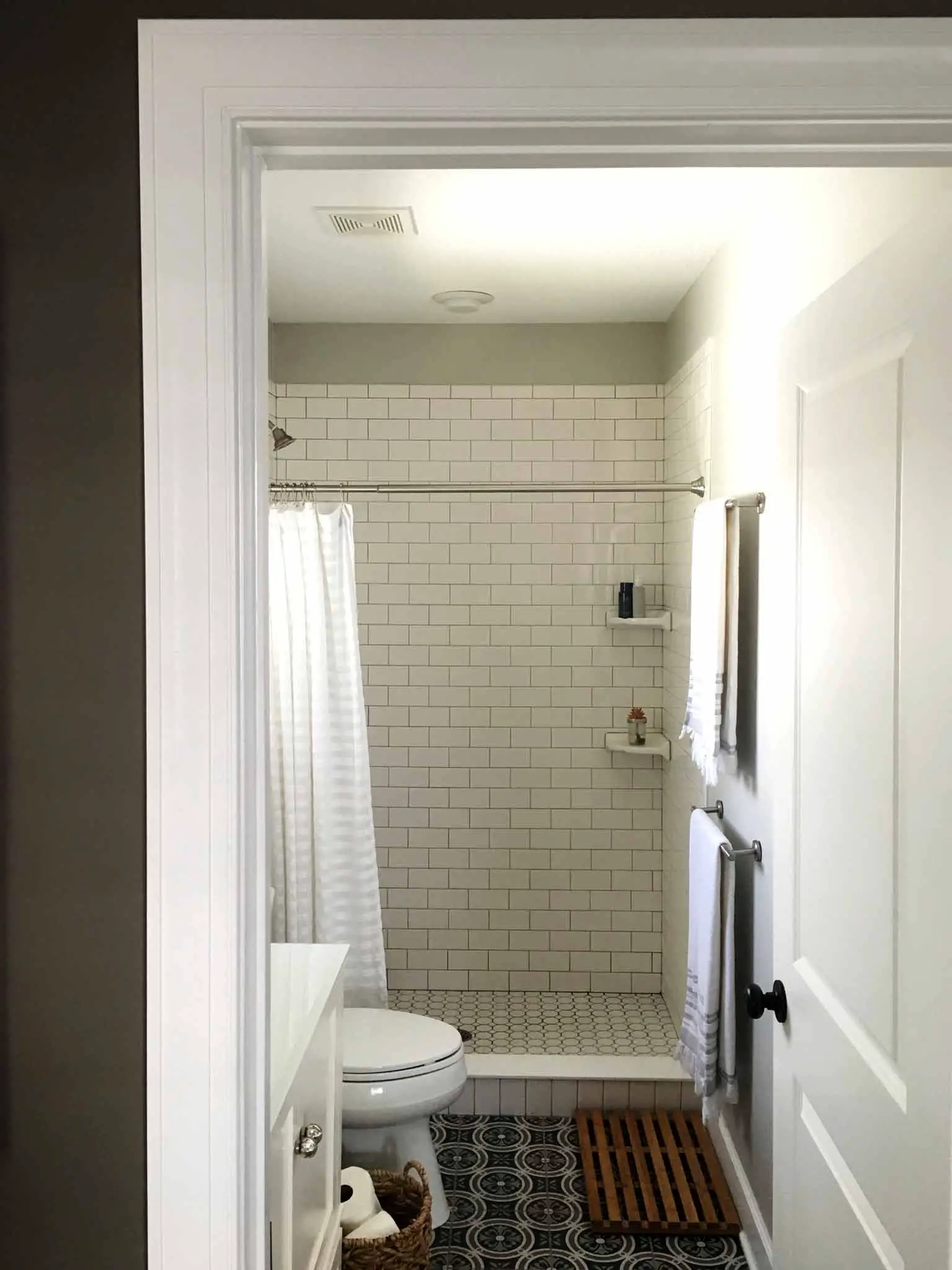 Bathroom with patterned ceramic floor tile, white subway tile and white vanity - That Homebird Life Blog