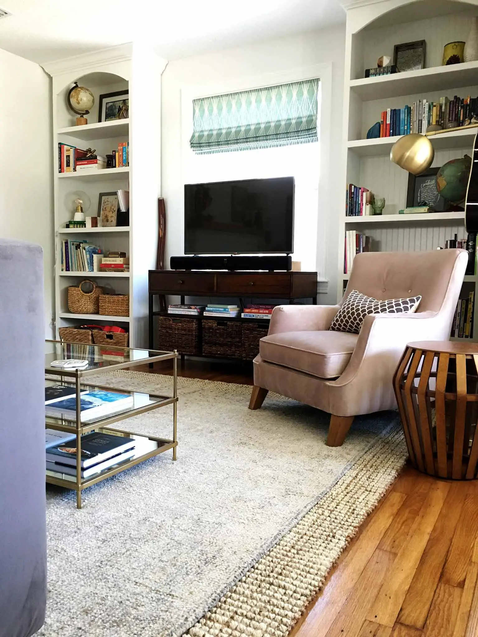 Living room after the refresh | layered rugs, glass coffee table, blush velvet accent chair, gold accents, built-in bookcases | That Homebird Life Blog