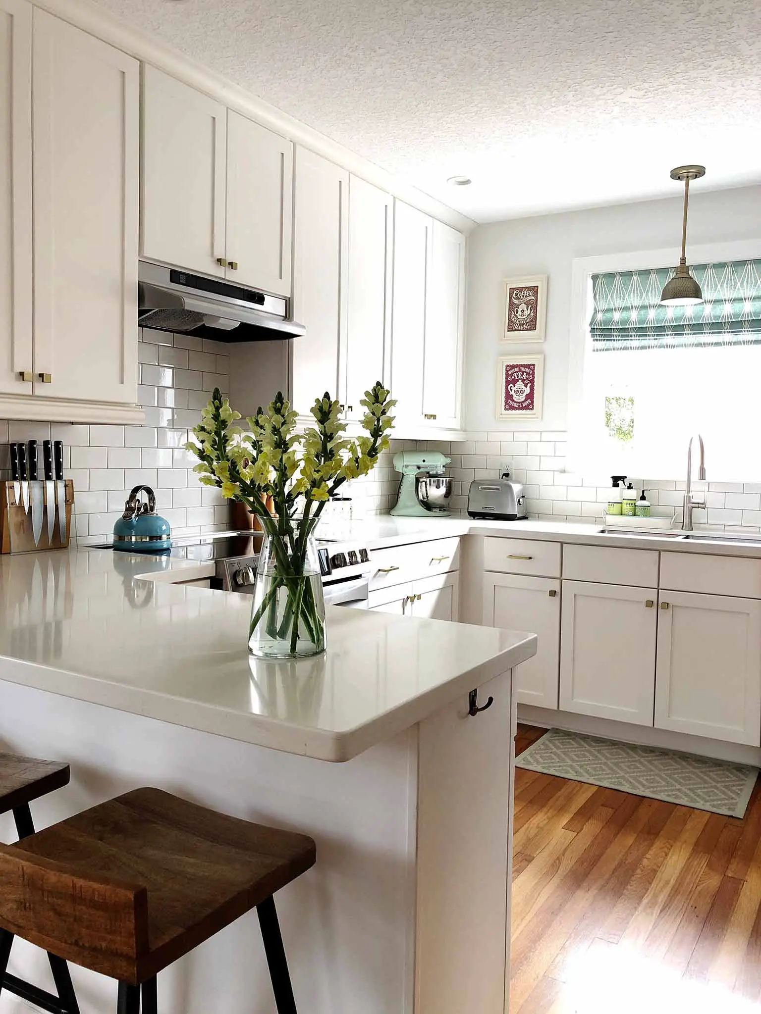 Clean white kitchen with vase of flowers on the penisular