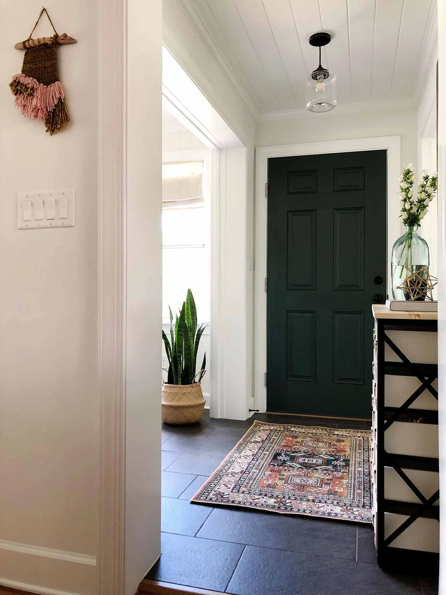 entryway with dark green door and patterned rug