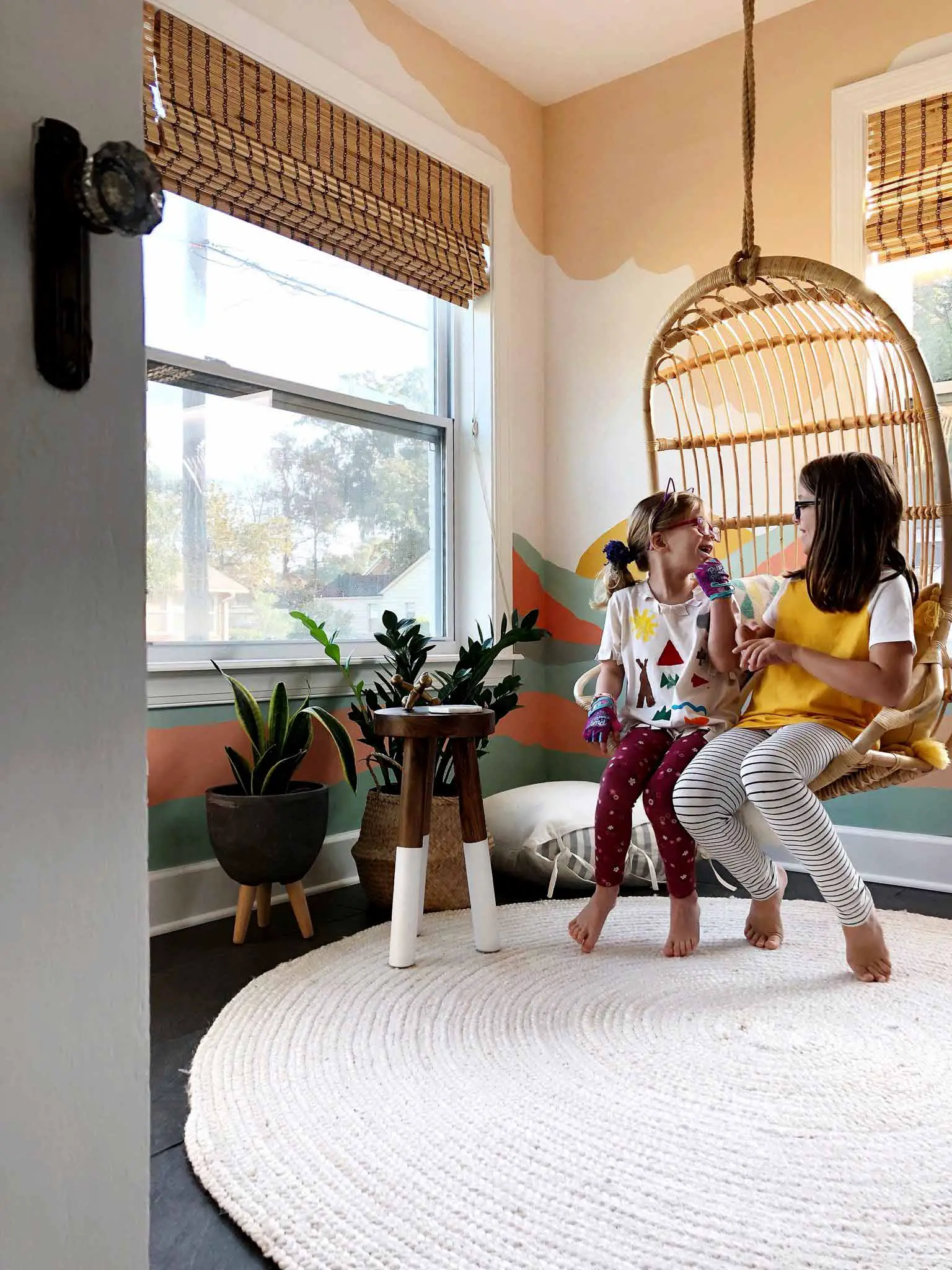 playroom with colorful mural and two girls in hanging chair