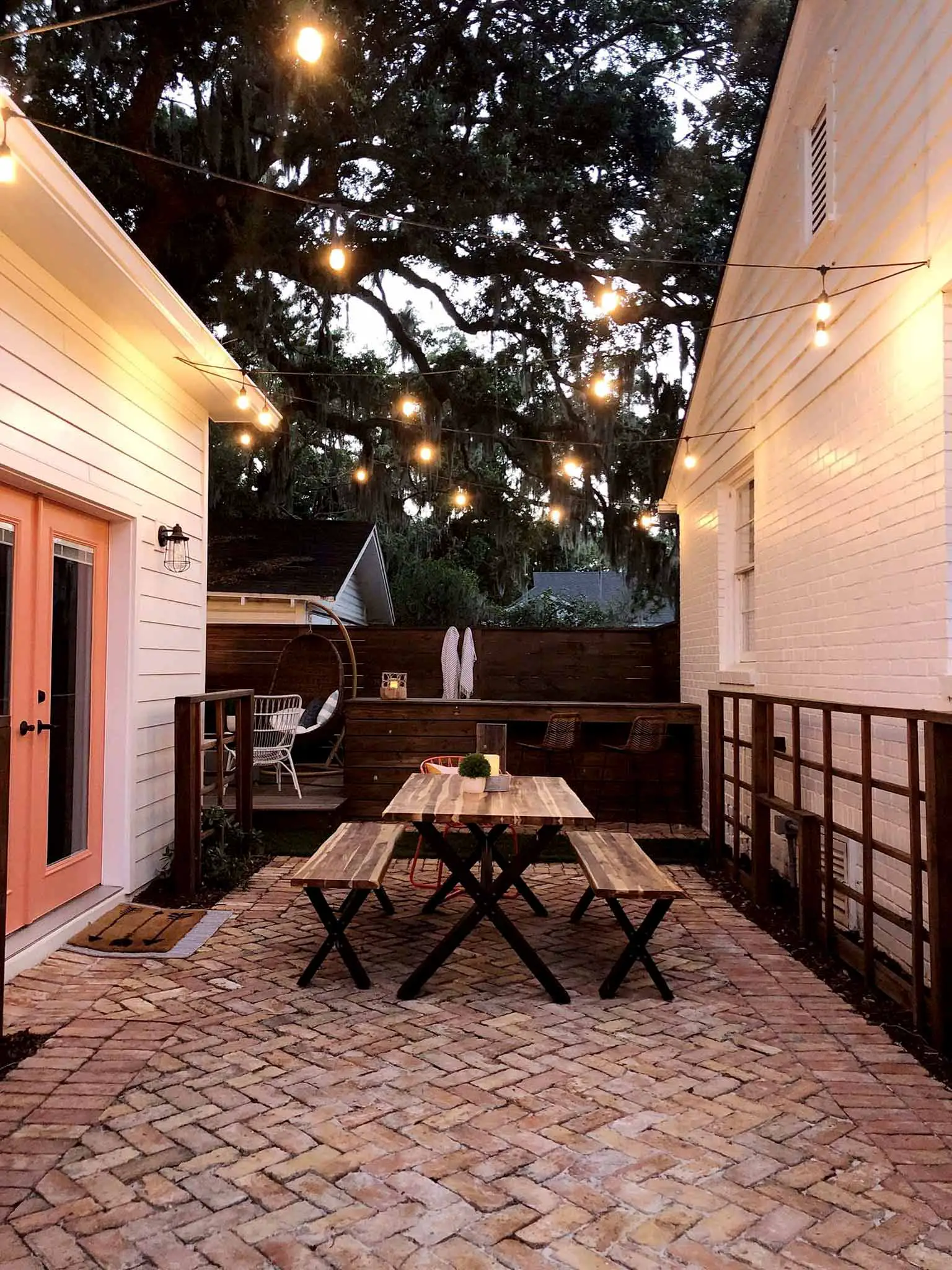 brick patio with table and benches under string lights