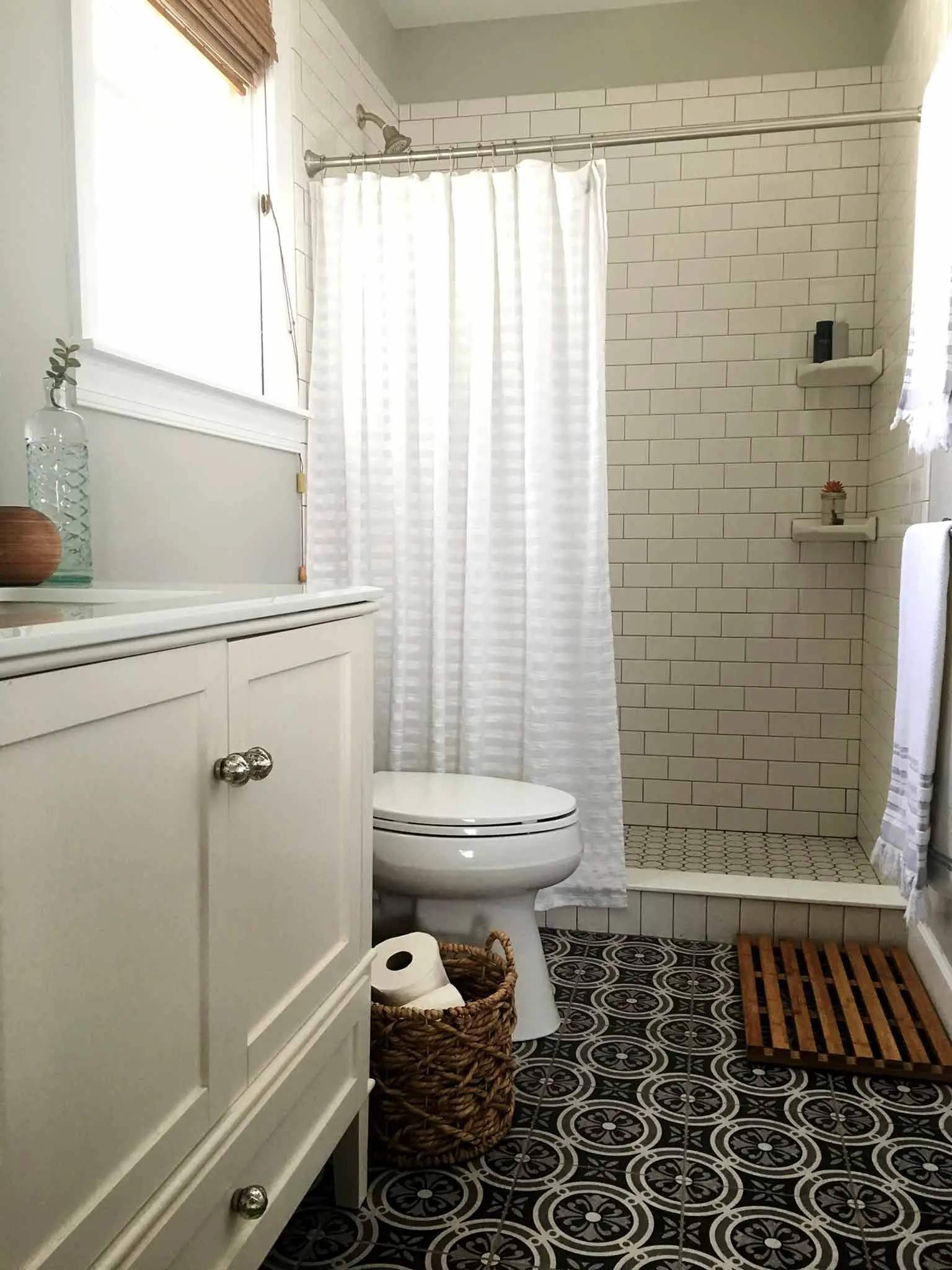 Bathroom with patterned ceramic floor tile, white subway tile and white vanity - That Homebird Life Blog