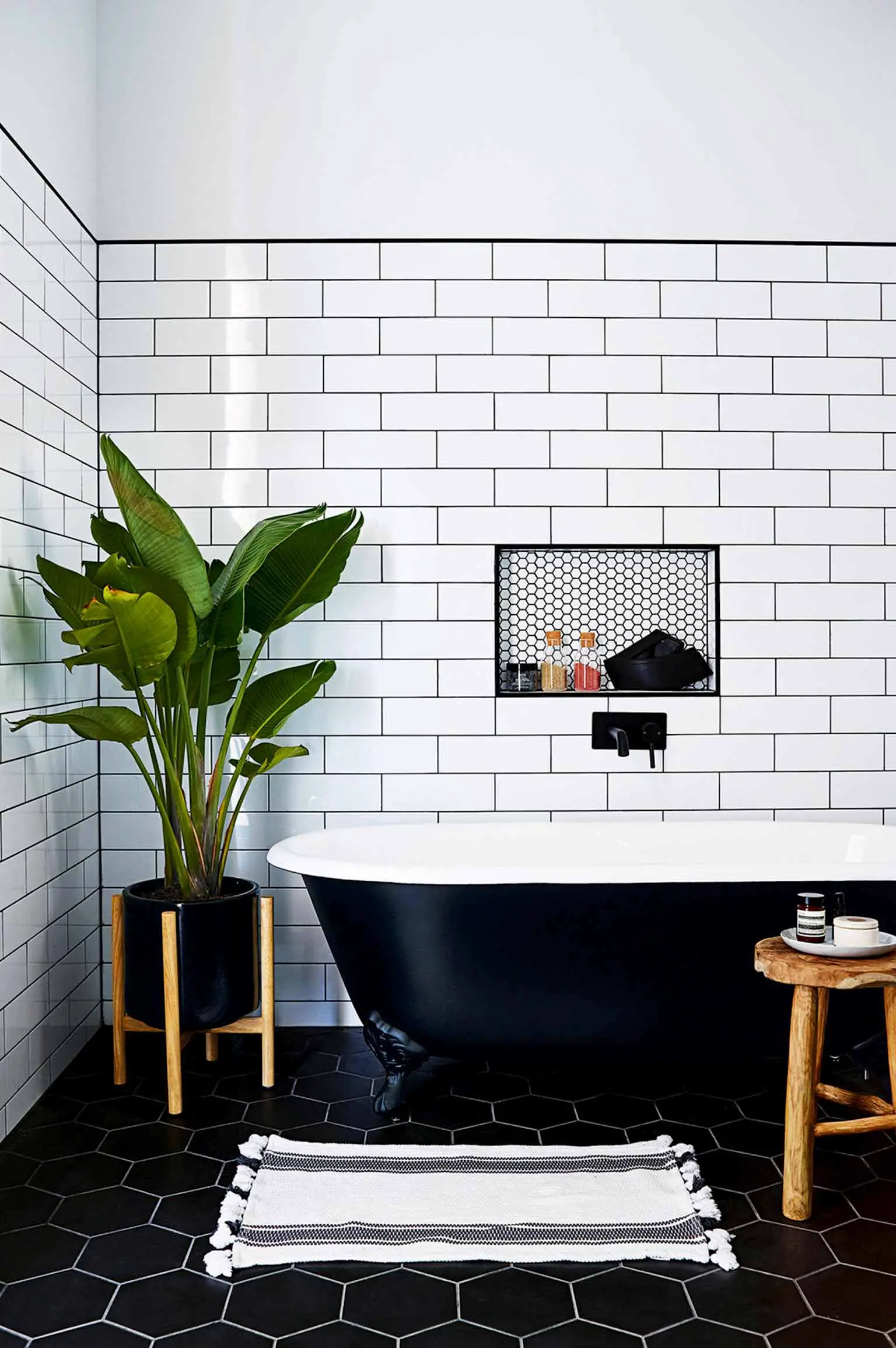 Bathroom with black hex floor tile, white subway tile with dark grout and matte black accents - That Homebird Life Blog