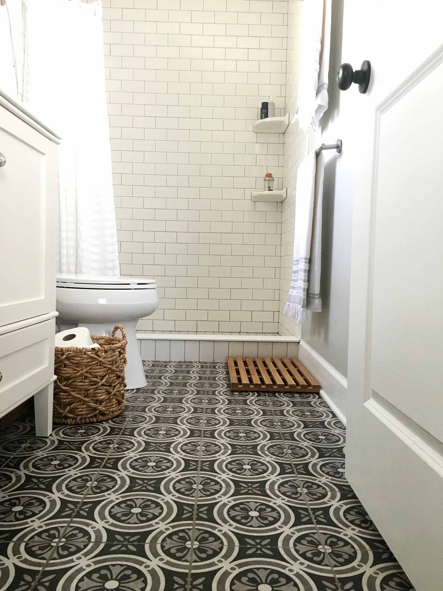 Bathroom with patterned ceramic floor tile, white subway tile and white vanity - That Homebird Life Blog