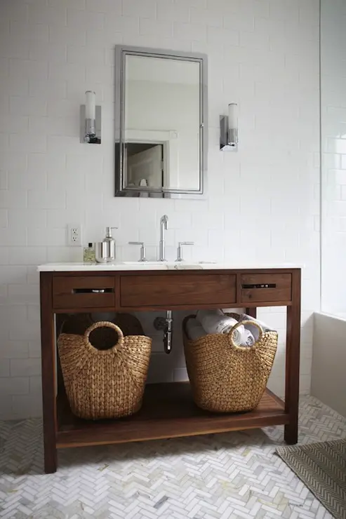 Bathroom with marble herringbone floor tile, white subway tile, wooden vanity and polished chrome accents - That Homebird Life Blog