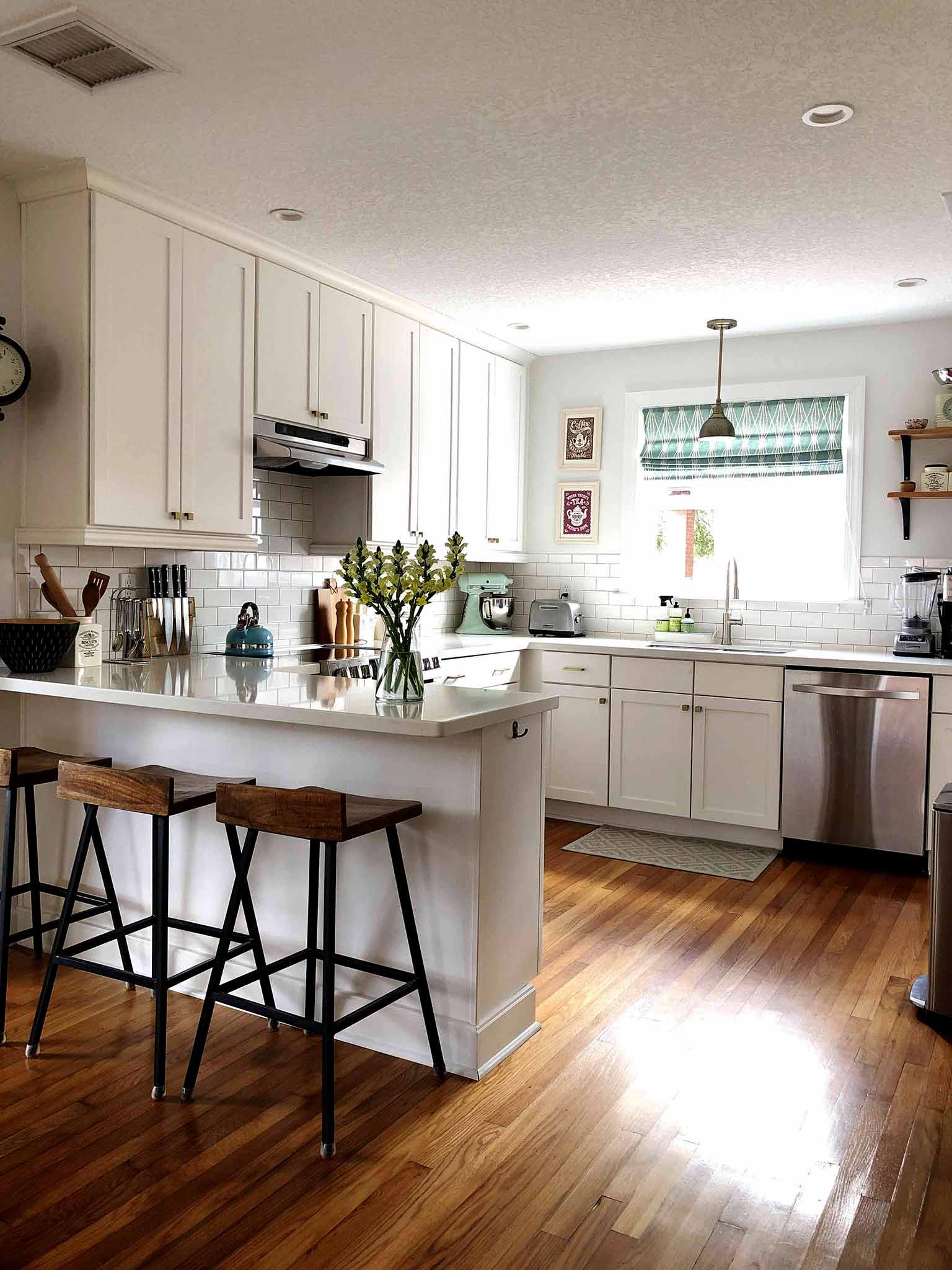 open concept kitchen with white cabinets, white subway tile and hardwood floors