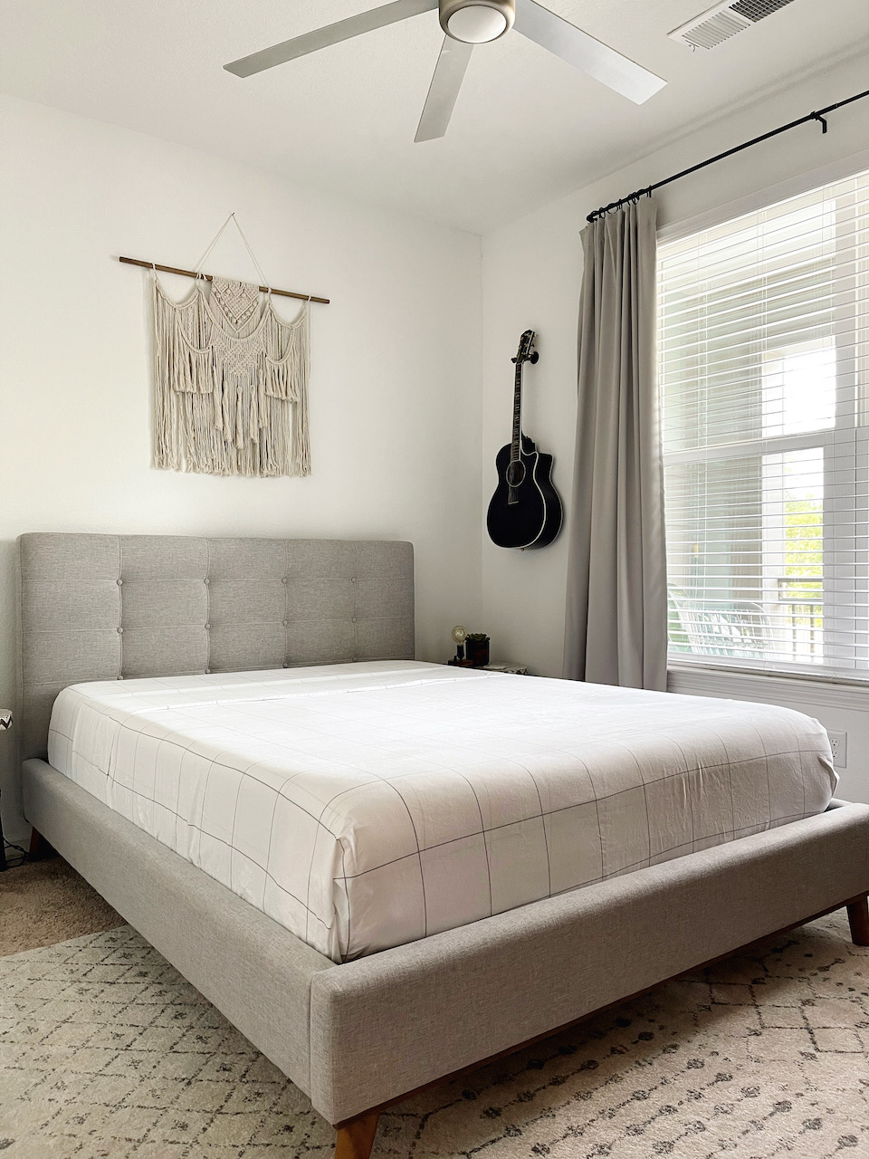 bedroom with queen bed and guitar on the wall