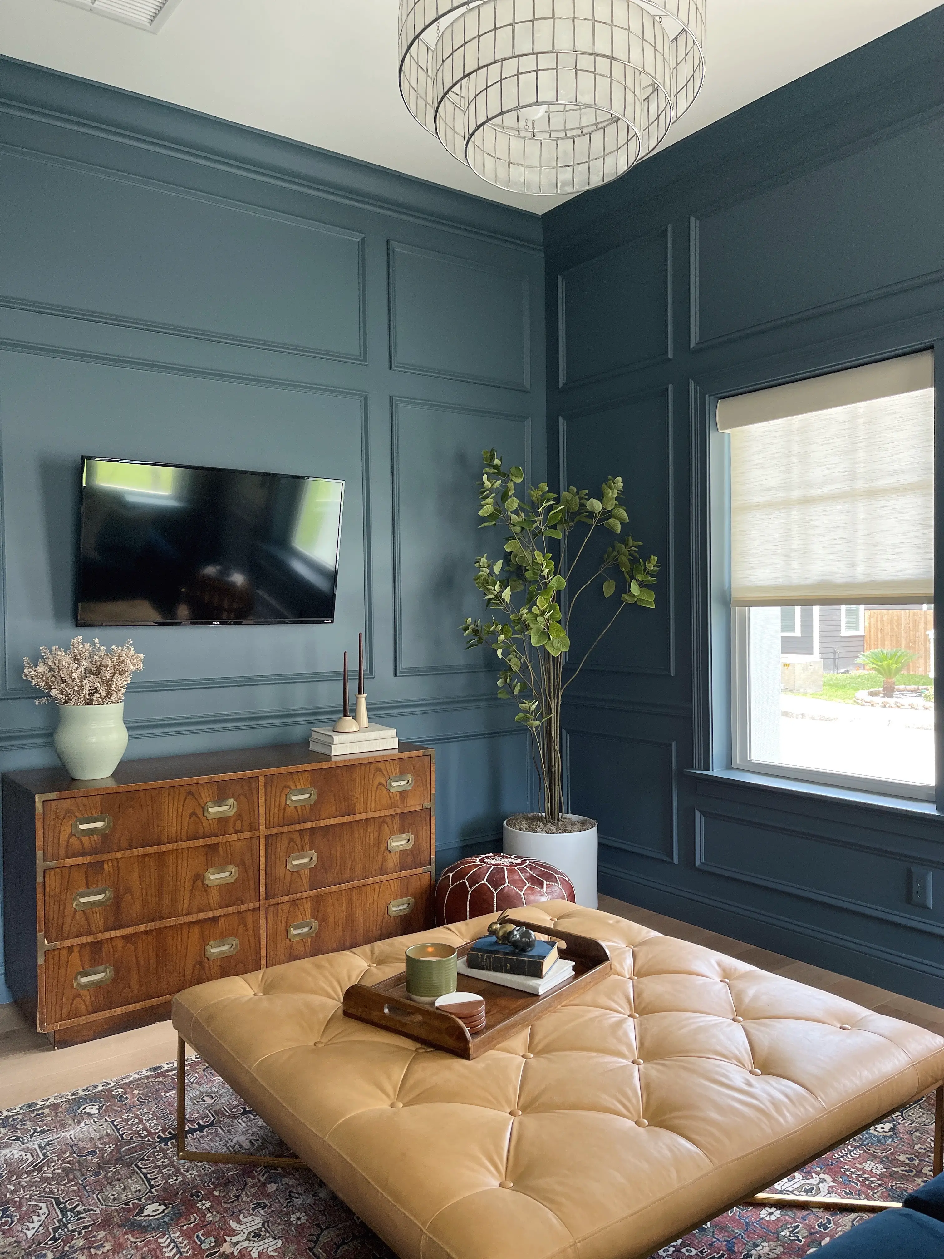 living room with blue picture molding, leather ottoman and blue velvet sofa